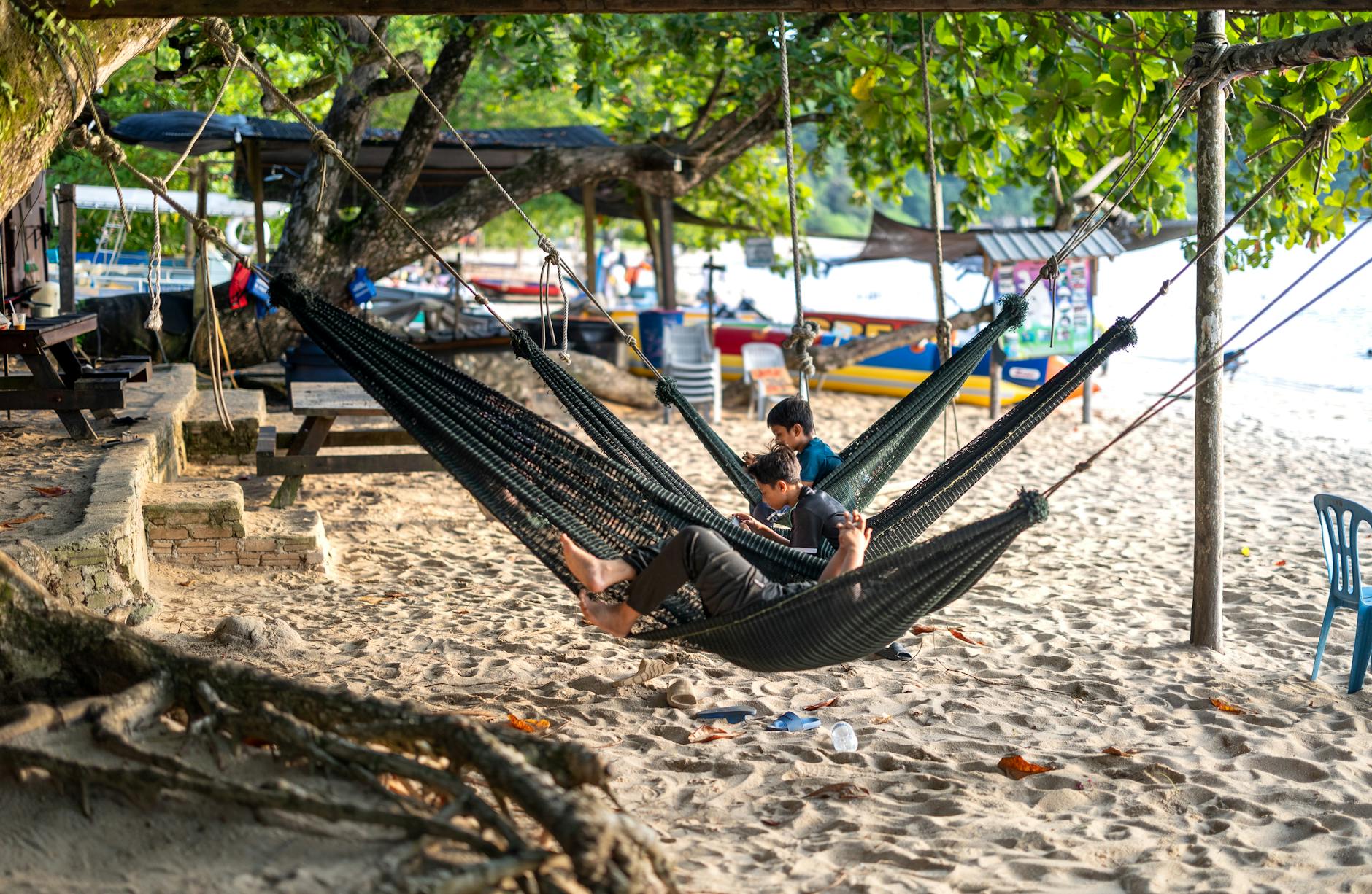 Malezja z dziećmi: bezpieczna i kolorowa przygoda pełna natury i nowych smaków Dzieci odpoczywające w hamakach na piaszczystej plaży Pangkor w Malezji