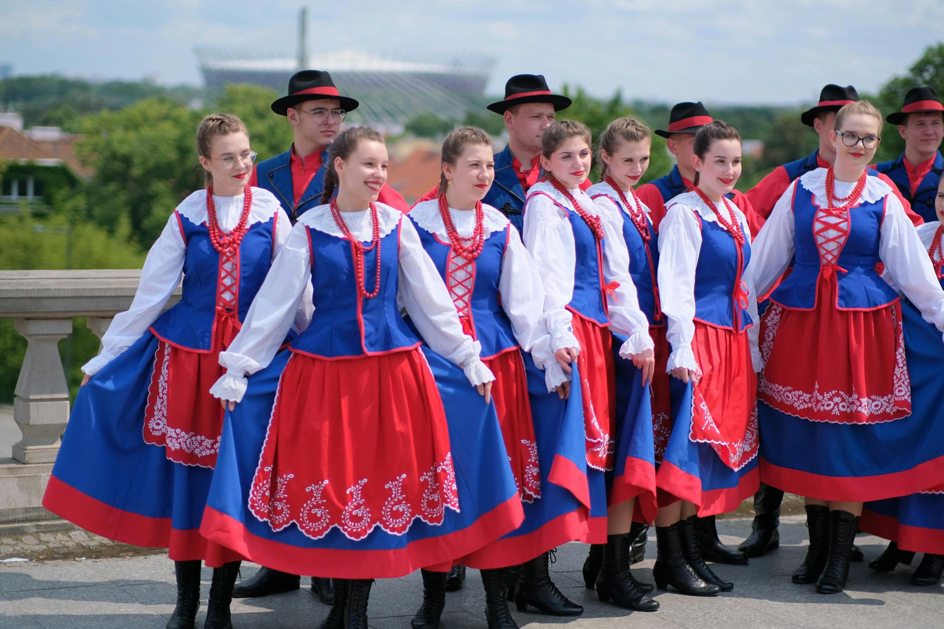 Grupa osób w polskich strojach ludowych pozuje do zdjęcia na dworze