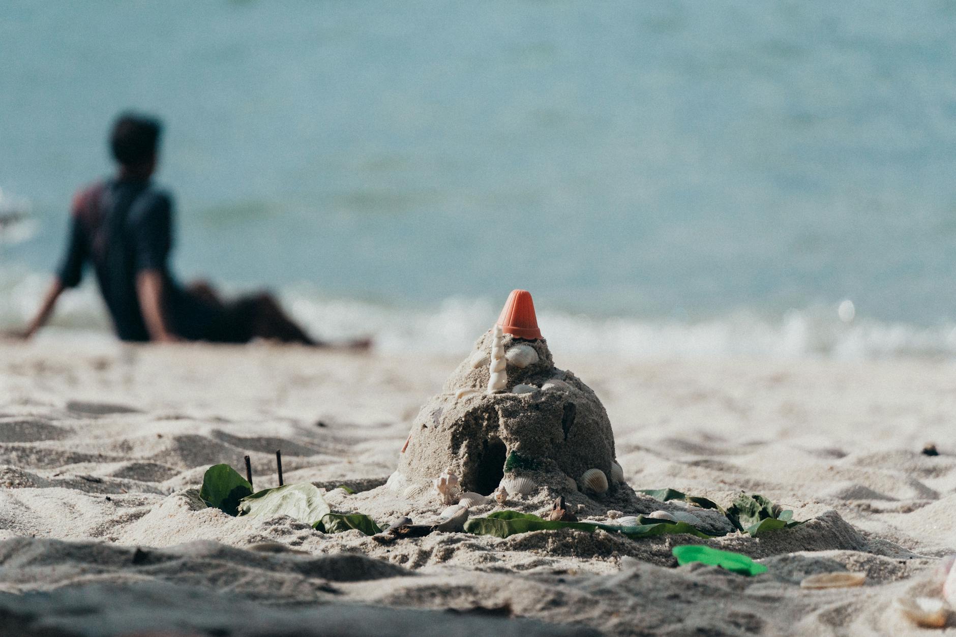 Zamek z piasku na malezyjskiej plaży i sylwetka dziecka przy morzu