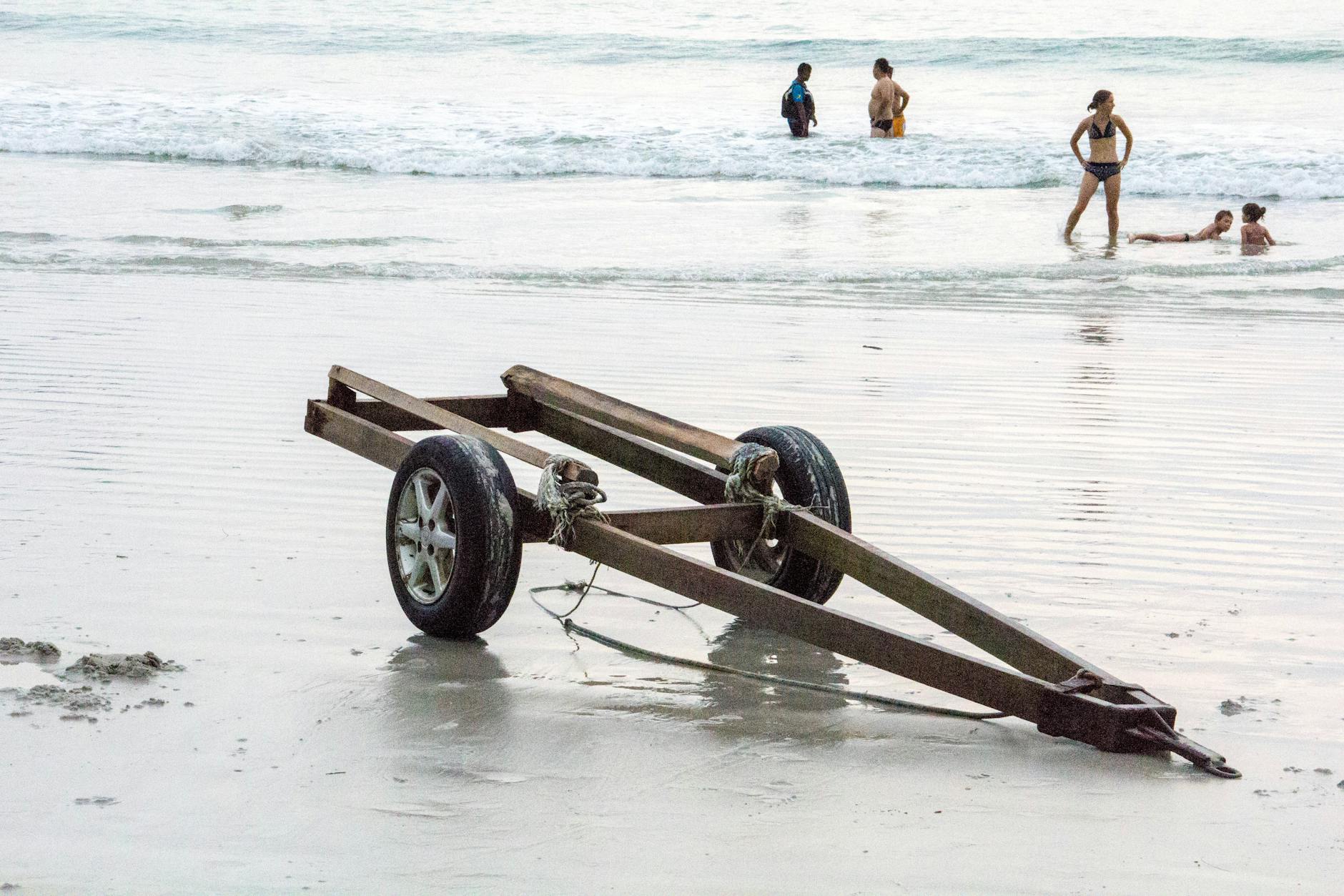 Zardzewiała przyczepa na plaży Langkawi, ludzie kąpią się w morzu