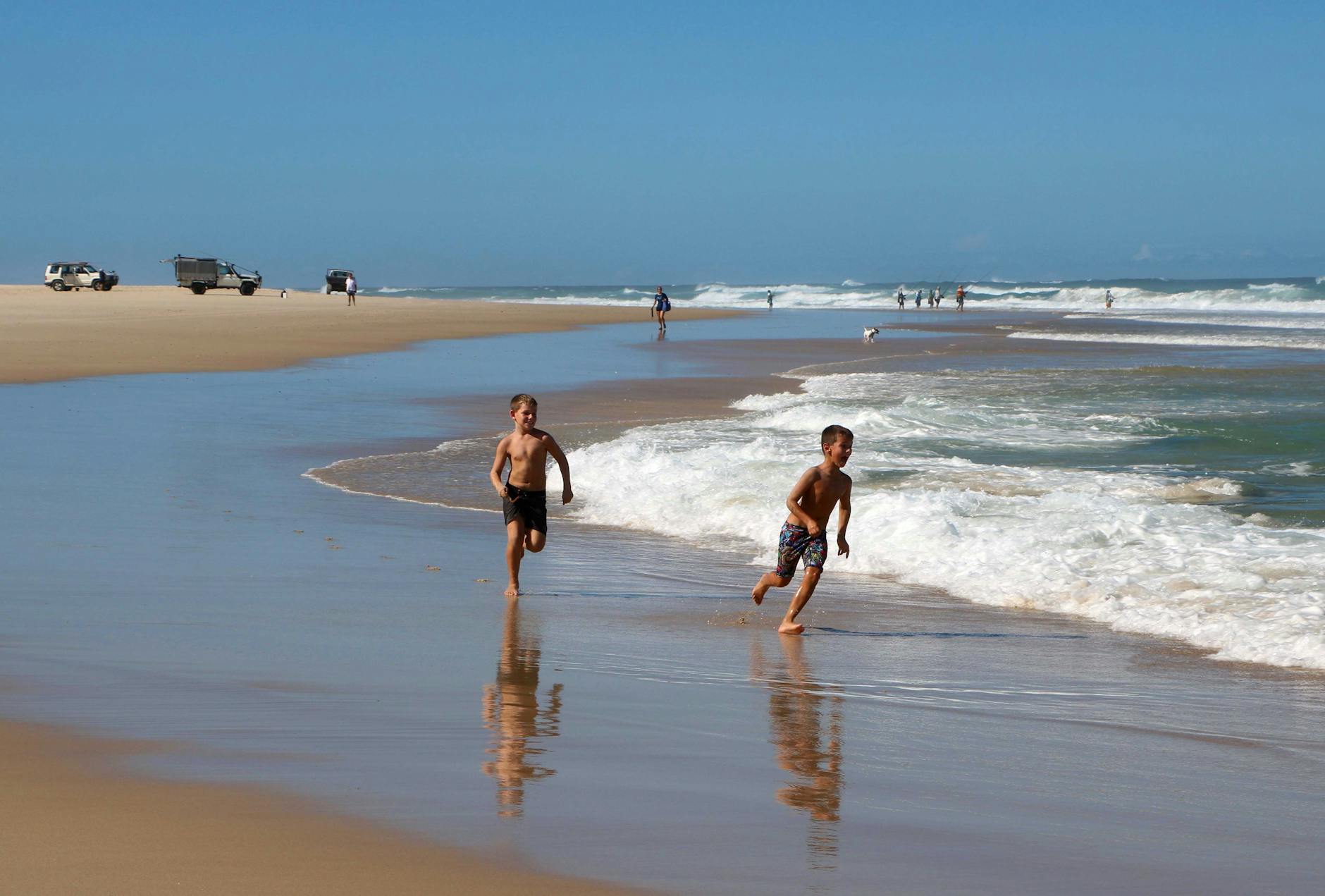 Dwóch chłopców biegnie po piaszczystej plaży Gold Coast latem