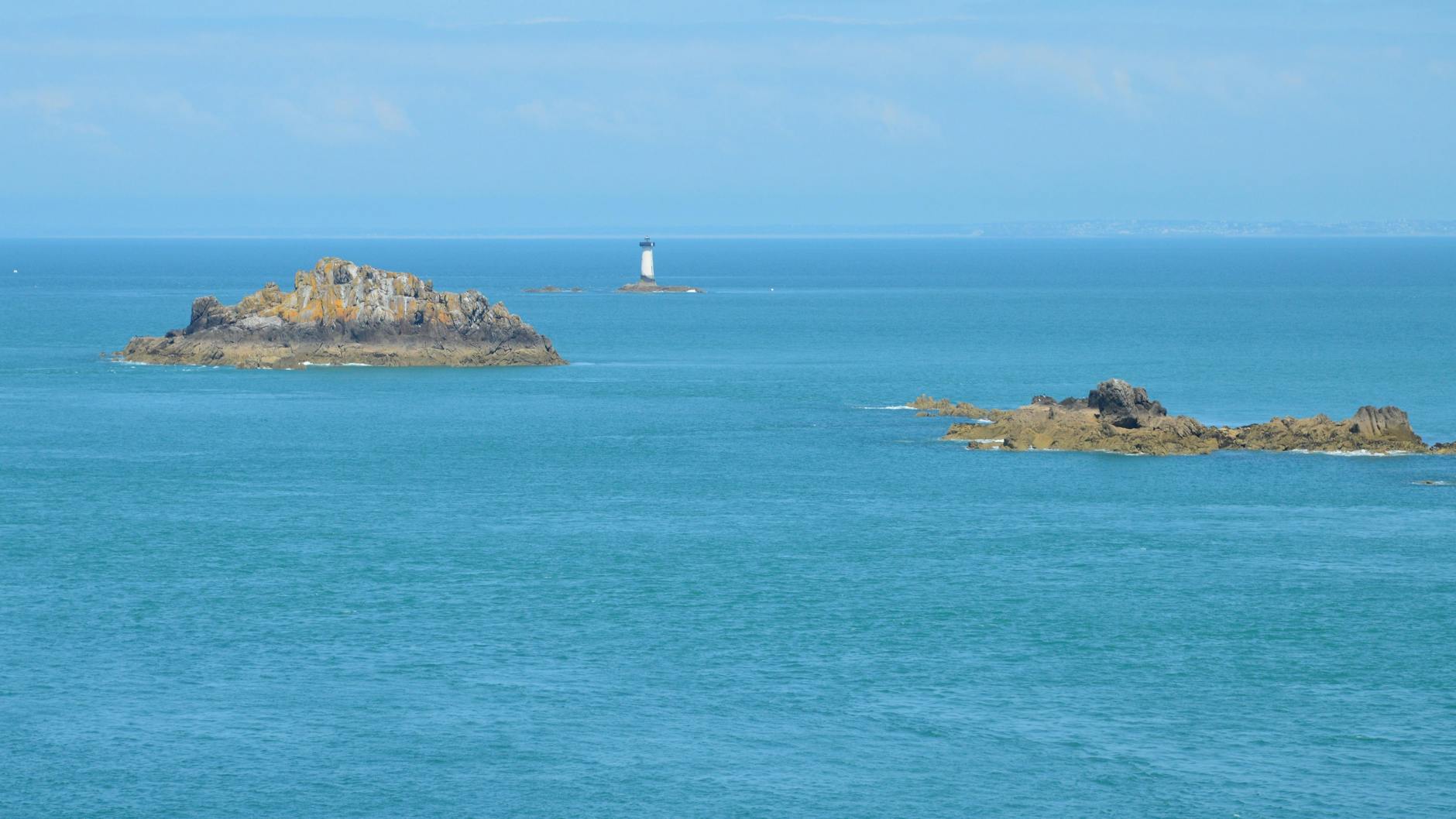 Latarnia morska w Cancale otoczona skalistymi wysepkami na tle błękitnego morza