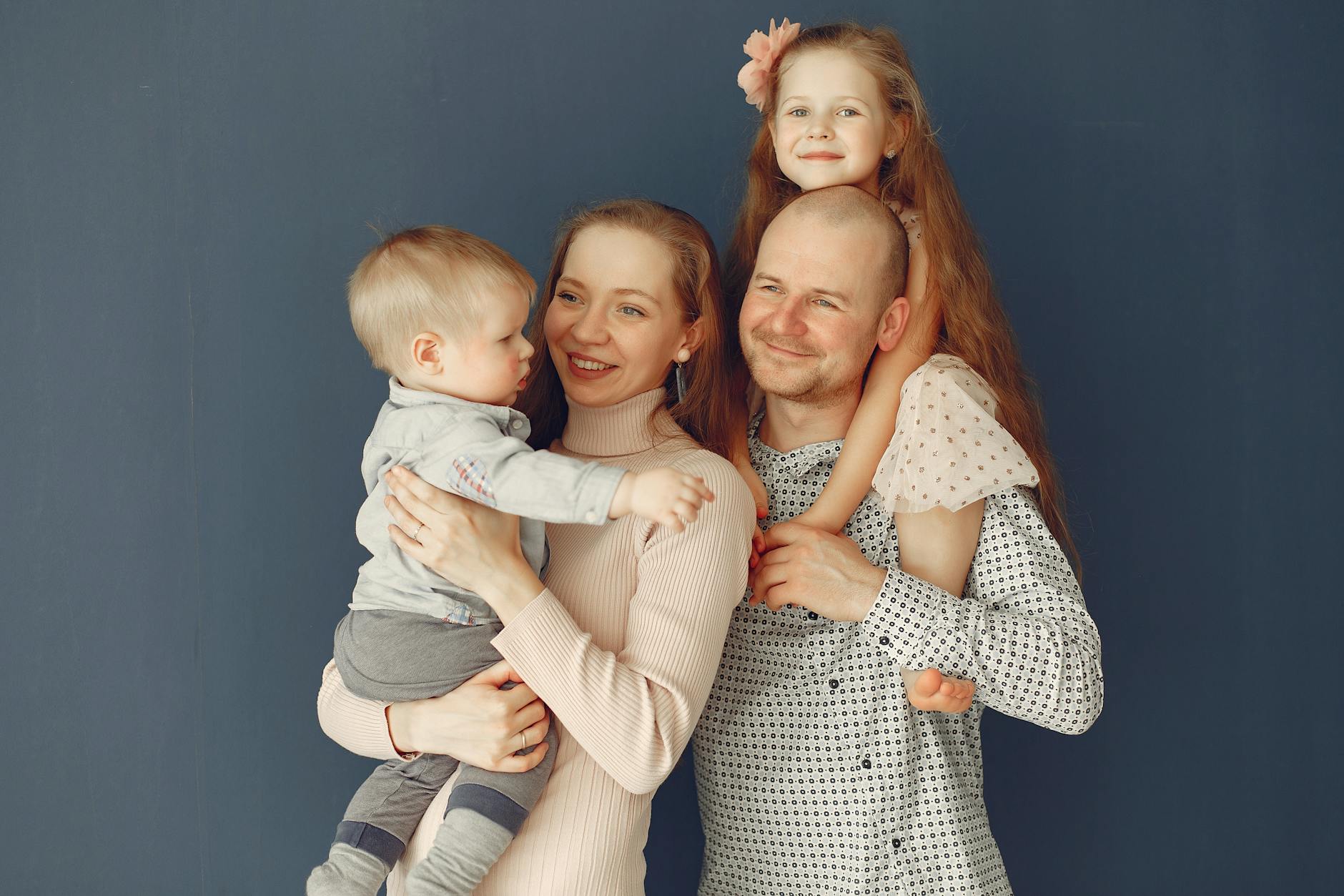 Uśmiechnięci rodzice z dwojgiem dzieci pozują razem do rodzinnego zdjęcia