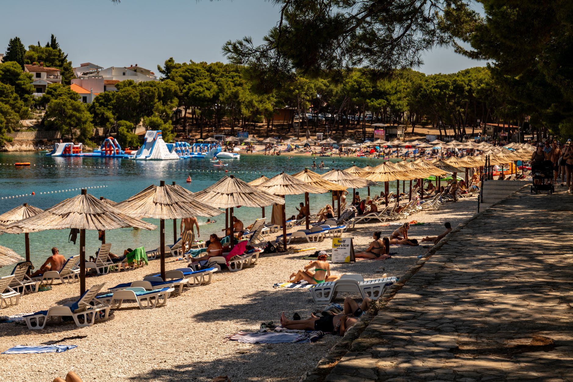 Rodziny na słonecznej plaży w Primošten w Chorwacji pod parasolami
