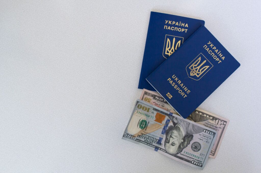 Dwa ukraińskie paszporty i banknoty dolarowe na białym tle